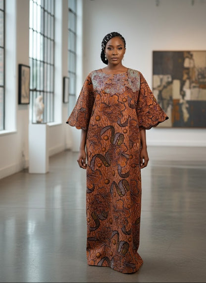 Woman in a patterned dress standing in a modern indoor setting with large windows and artwork.