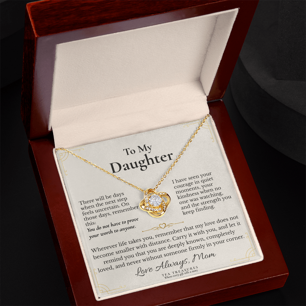 A gold heart-shaped pendant necklace with a clear crystal center, displayed on a printed message card inside an open dark wood gift box. The card is addressed 'To My Daughter' and features a sentimental message, with the brand 'TEA & TEARDROPS' visible at the bottom.