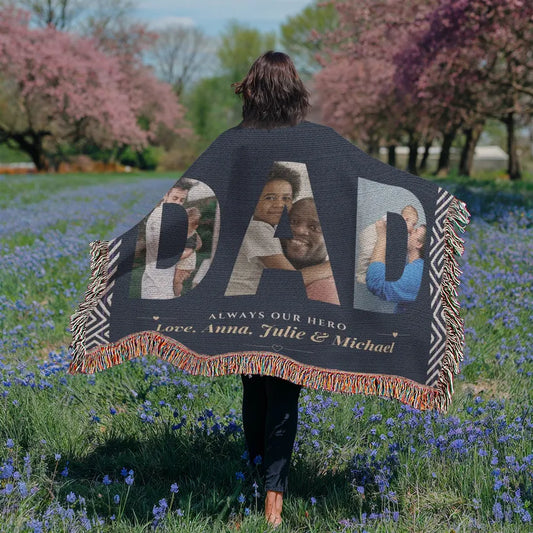 Person holding a personalized blanket with family photos and text in a field of flowers.